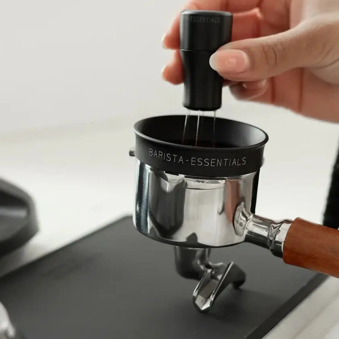 Zwarte doseerring op portafilter tijdens WDT om morsen te beperken en rustiger espresso voor te bereiden