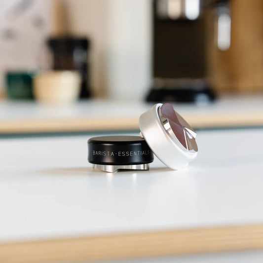 Een professionele barista gebruikt een 85,5mm koffieverdeler voor een gelijkmatige koffiepuck.