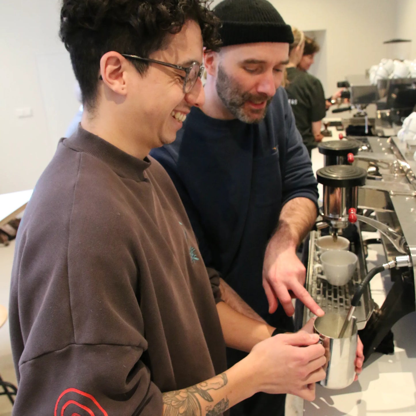 Workshopdeelnemers oefenen met espressomachines onder begeleiding van een professionele barista in Amsterdam.