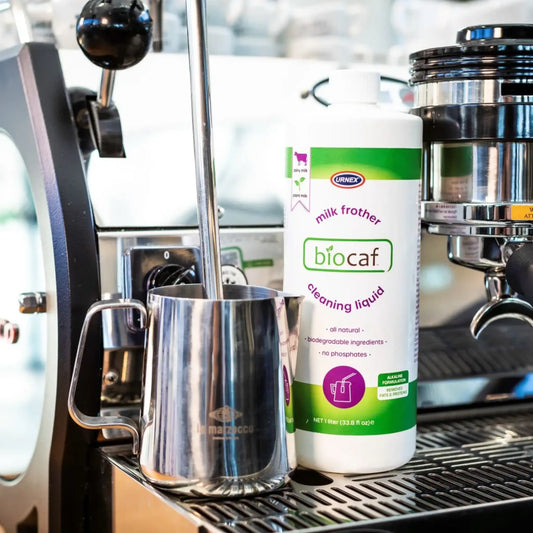 Biocaf milk frother cleaning liquid fles naast La Marzocco espressomachine met stoompijp en melkkan – geschikt voor zuivel en plantaardige melk.