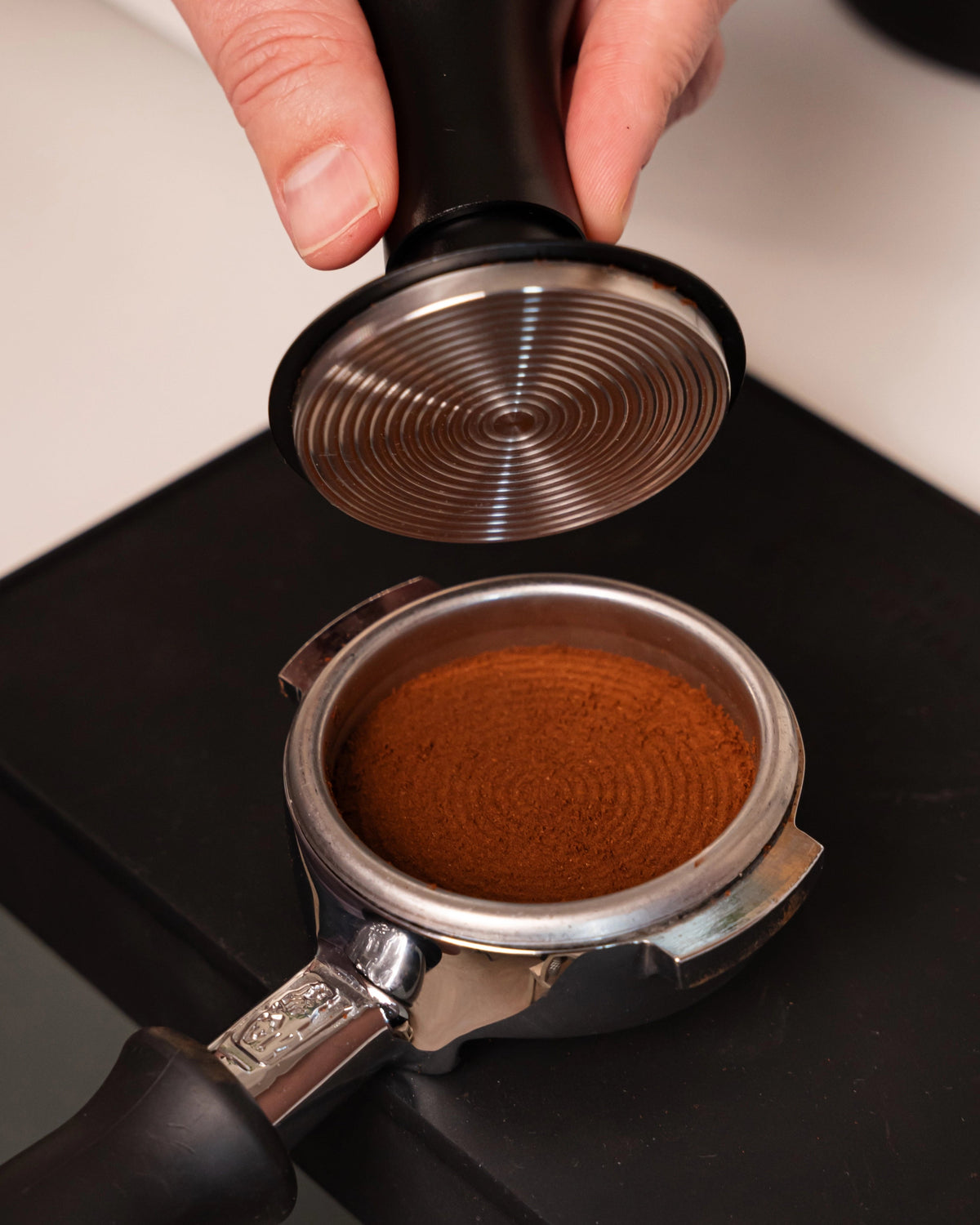 Geribbeld tampvlak van de 58,5 mm klik-tamper boven aangedrukte koffie