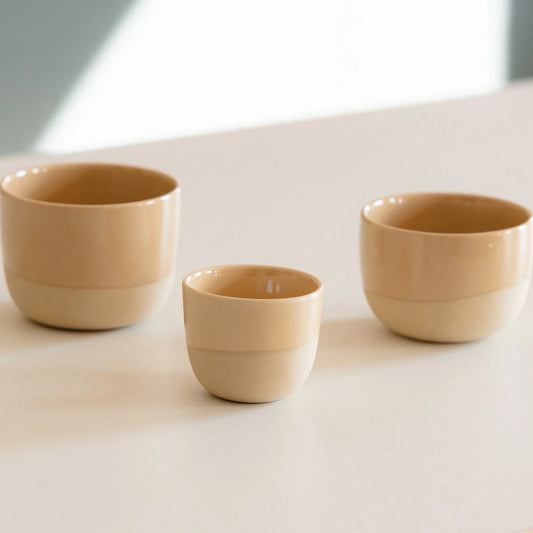 Drie zandgele porseleinen kopjes, waaronder een latte formaat van 250 ml – perfect voor thuisbarista’s met Philips, Krups of Gaggia machines. Handgemaakt, stapelbaar en ontworpen om jouw latte art tot z’n recht te laten komen.