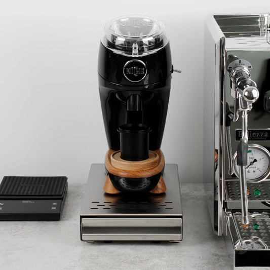 Koffiemolen op een zilveren uitkloplade naast een espressomachine