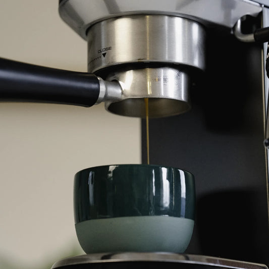 Naked portafilter 51 mm zwart voor DeLonghi Dedica: espresso boven een groen kopje