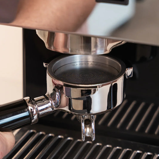 Quick Mill portafilter met 58 mm puck screen onder de zetgroep voor schonere extractie en minder koffieresten tegen de douchezeef.