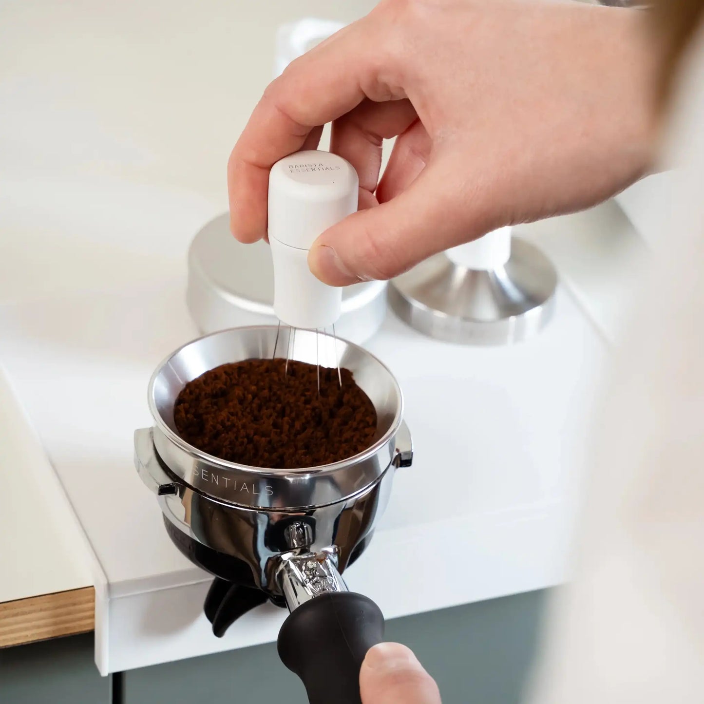 Witte WDT-tool in gebruik voor espresso puck-prep met portafilter, doseerring en gemalen koffie