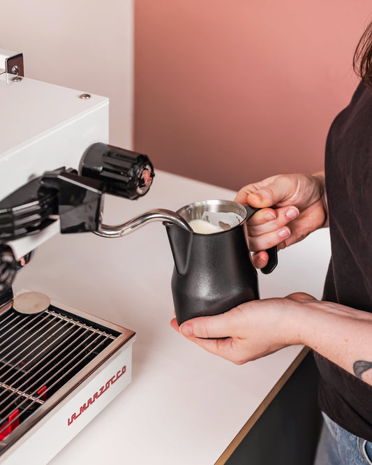 Zwarte Italiaanse melkkan 500 ml bij de stoompijp van een espressomachine