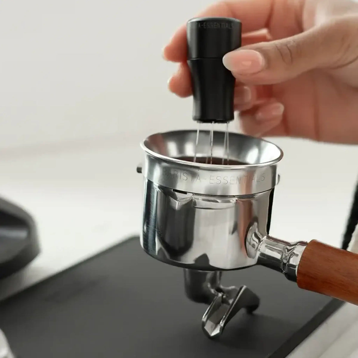 Zilveren doseerring op portafilter tijdens WDT voor schonere puck prep en minder koffie over de rand