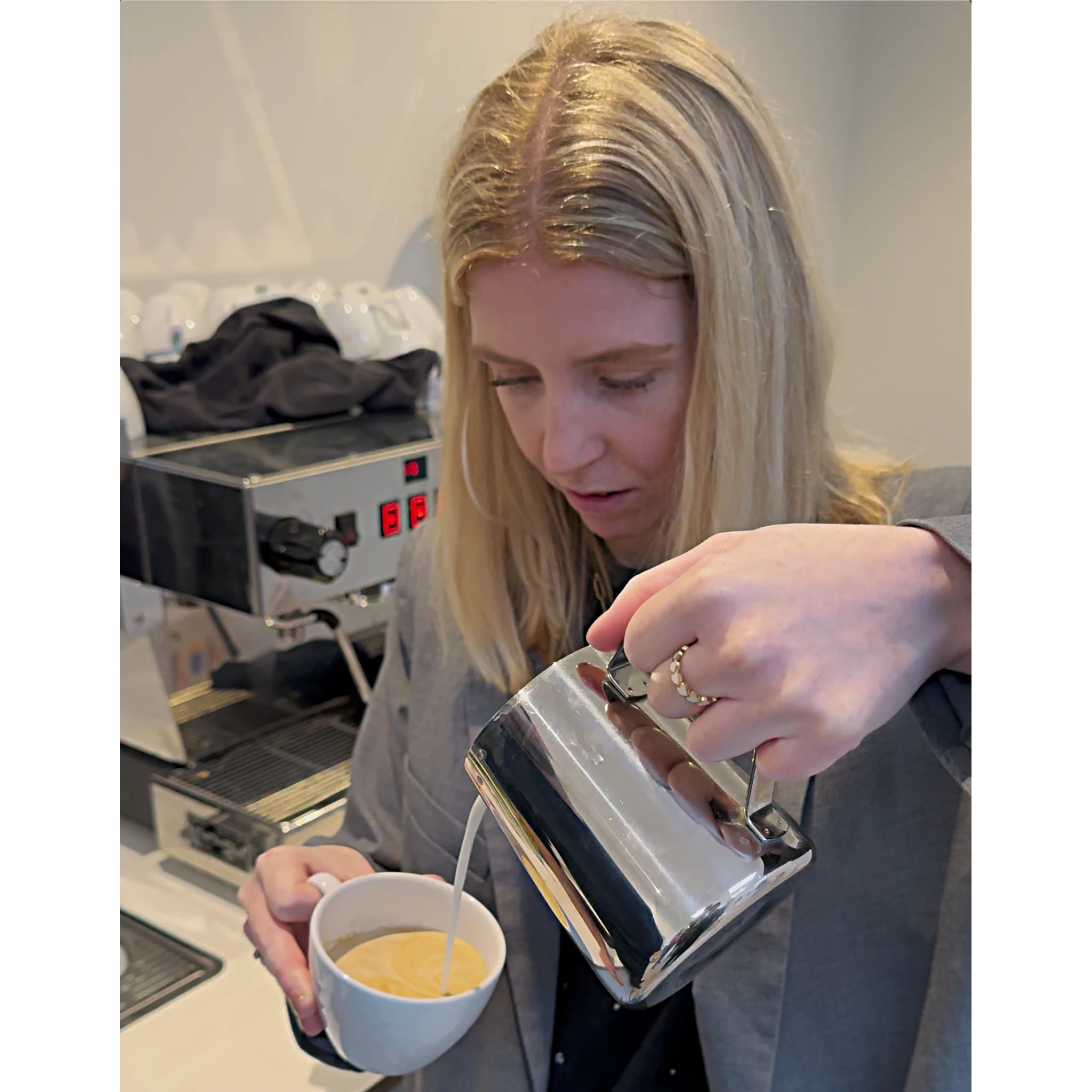 Een barista workshop deelnemer schenkt melk in een koffie kopje