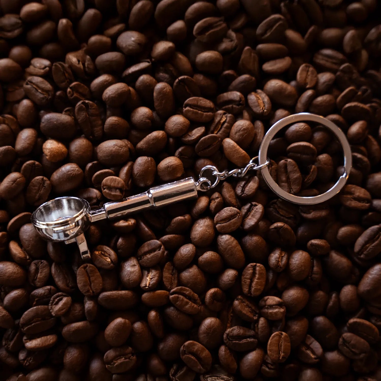 Barista filterdrager sleutelhanger ligt op gebrande specialty coffee koffiebonen