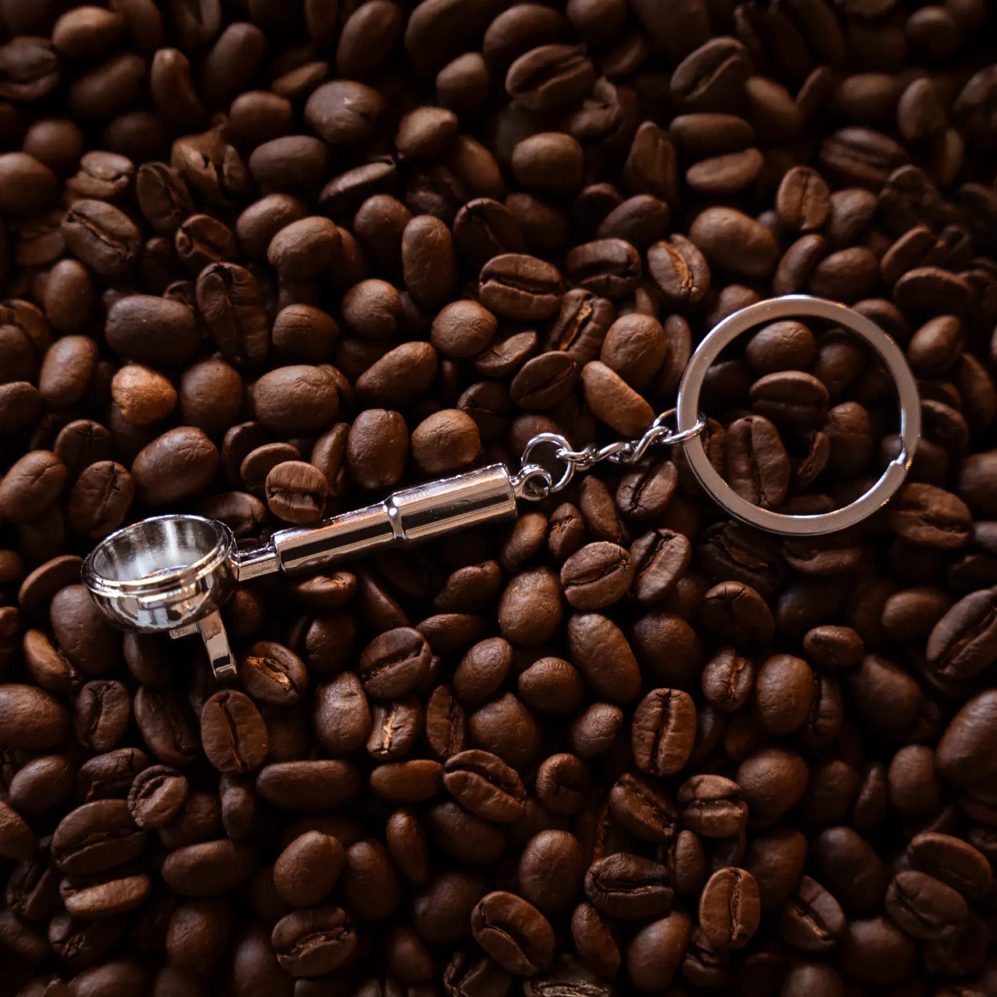 Barista filterdrager sleutelhanger ligt op gebrande specialty coffee koffiebonen