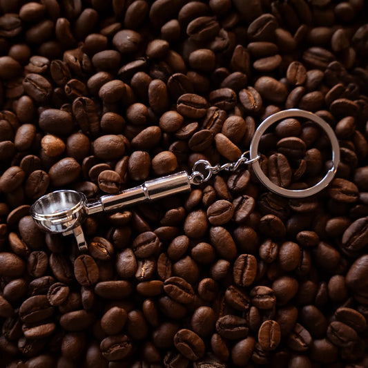 Barista filterdrager sleutelhanger ligt op gebrande specialty coffee koffiebonen