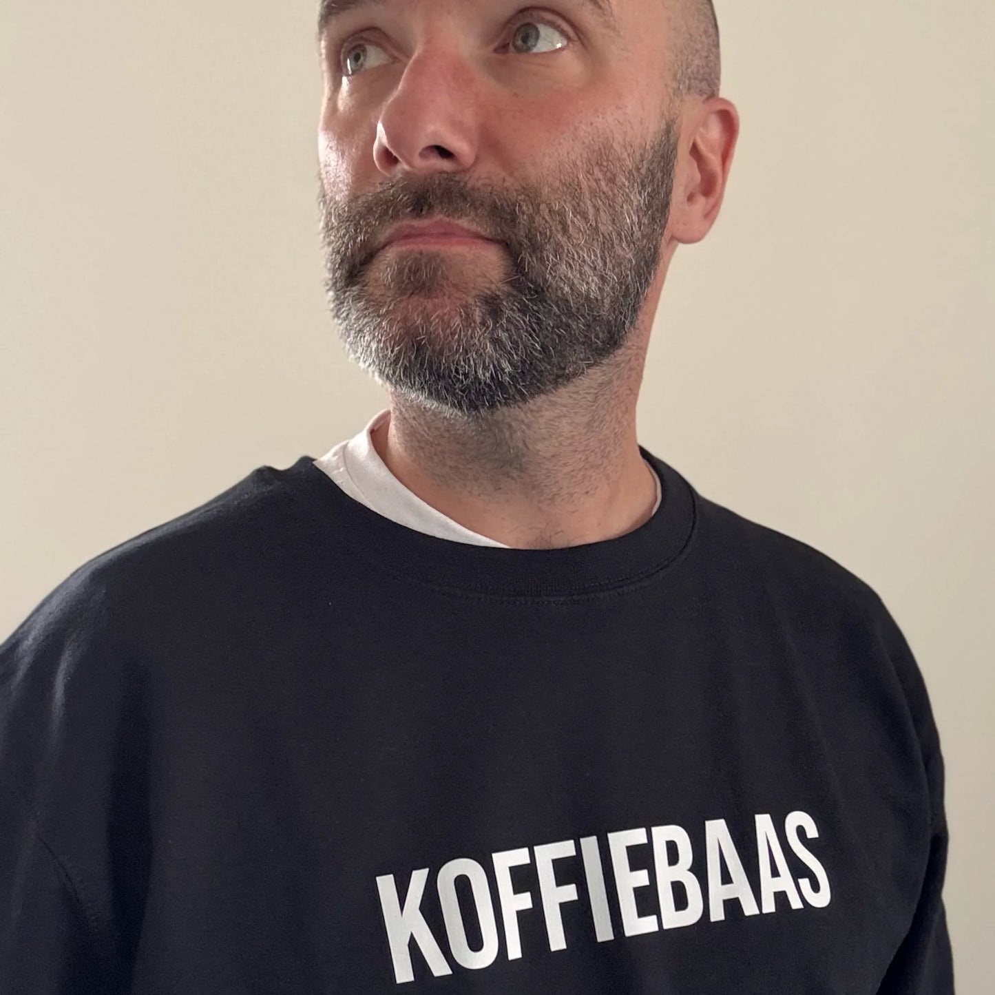 Man draagt zwarte “KOFFIEBAAS” sweater – ideaal barista cadeau