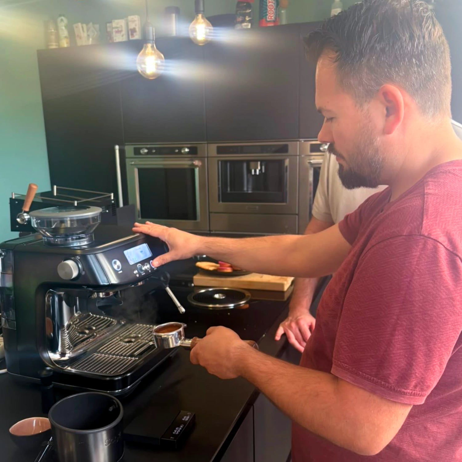 Deelnemer draait een gevulde filterdrager in de Sage Barista Pro tijdens een barista workshop aan huis op de eigen espressomachine.