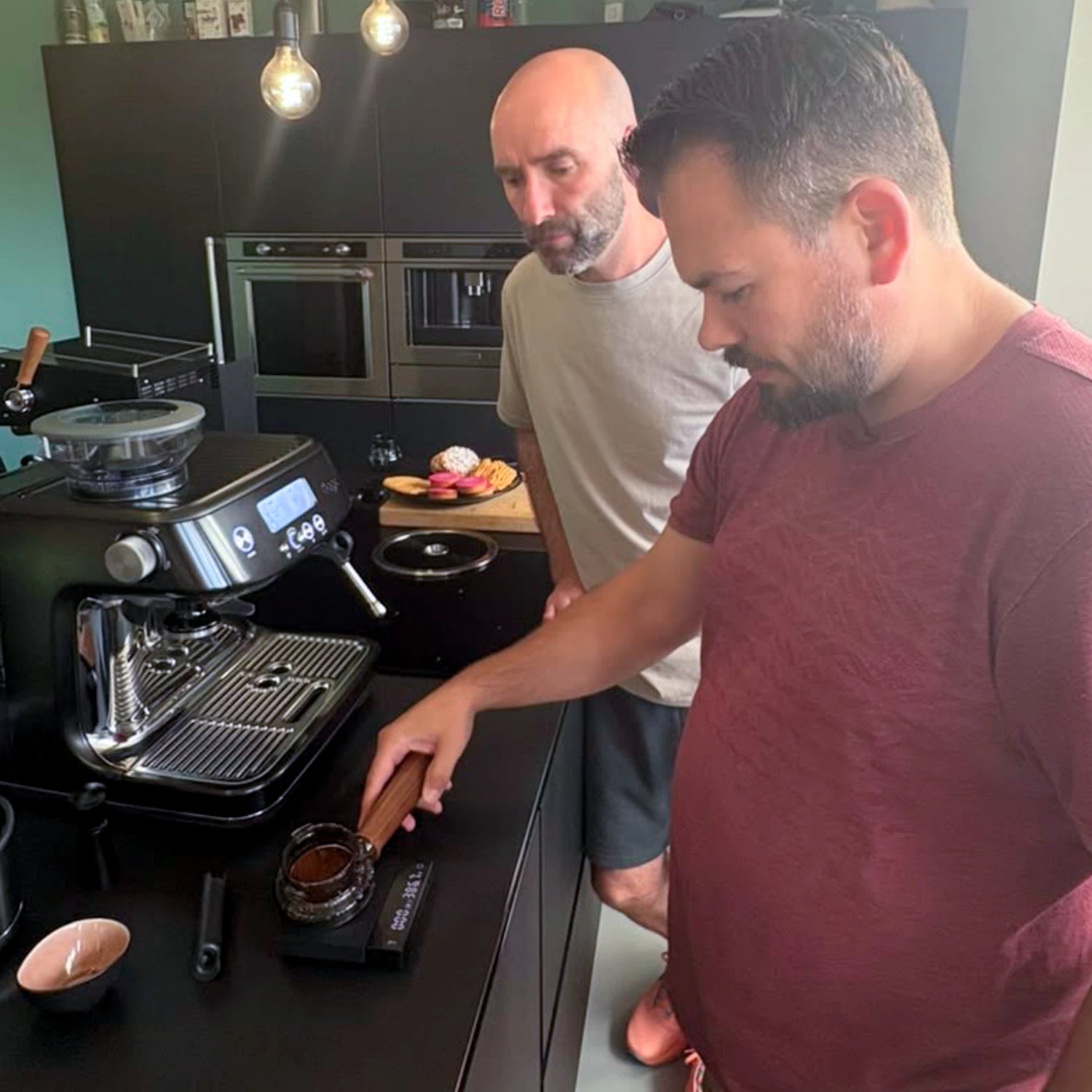 Deelnemer weegt gemalen koffie in een gevulde filterdrager op een digitale koffieweegschaal tijdens een barista workshop aan huis op de eigen Sage Barista Pro.