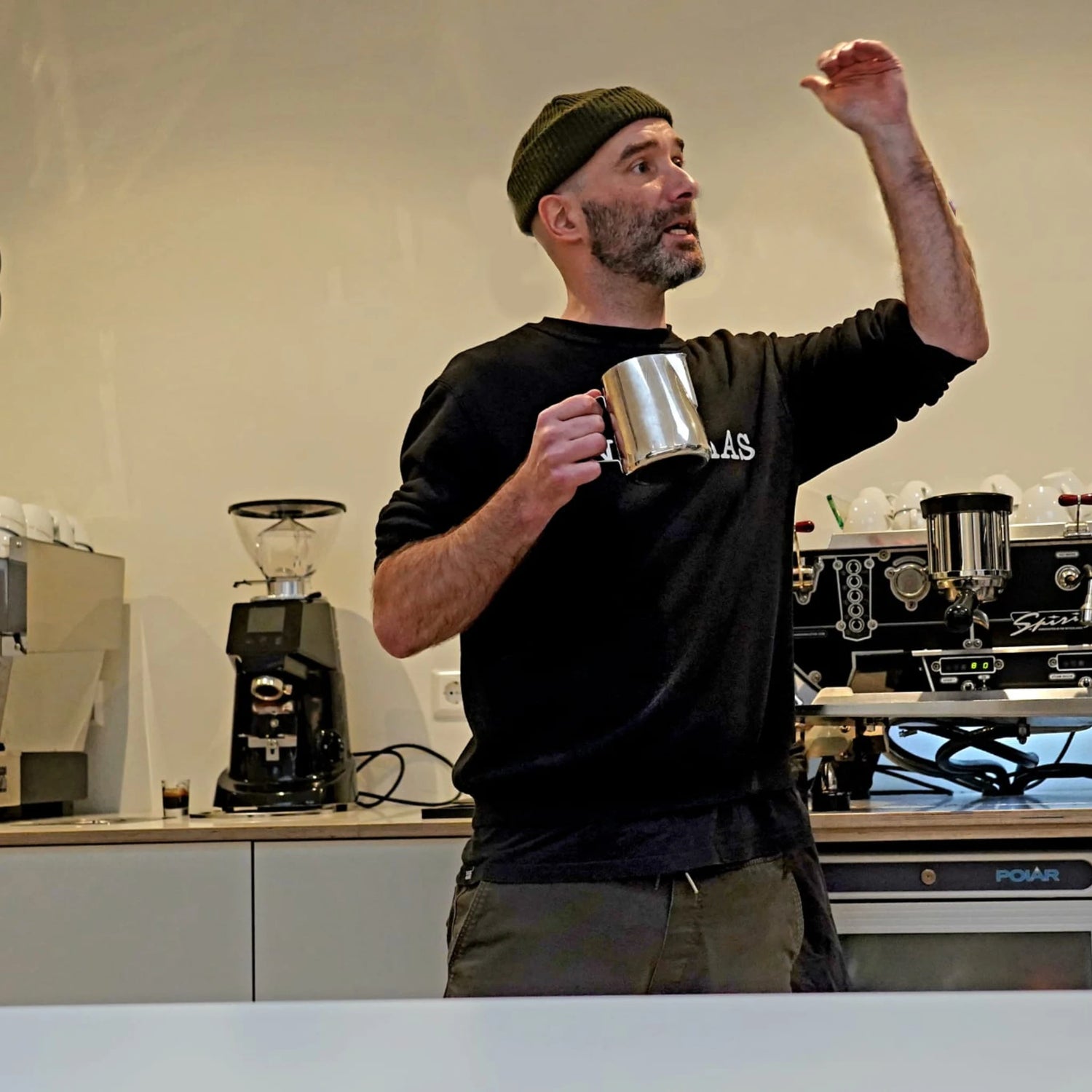 Geert-Jan de Baristaman geeft uitleg met een melkkan tijdens een barista workshop in Amsterdam.