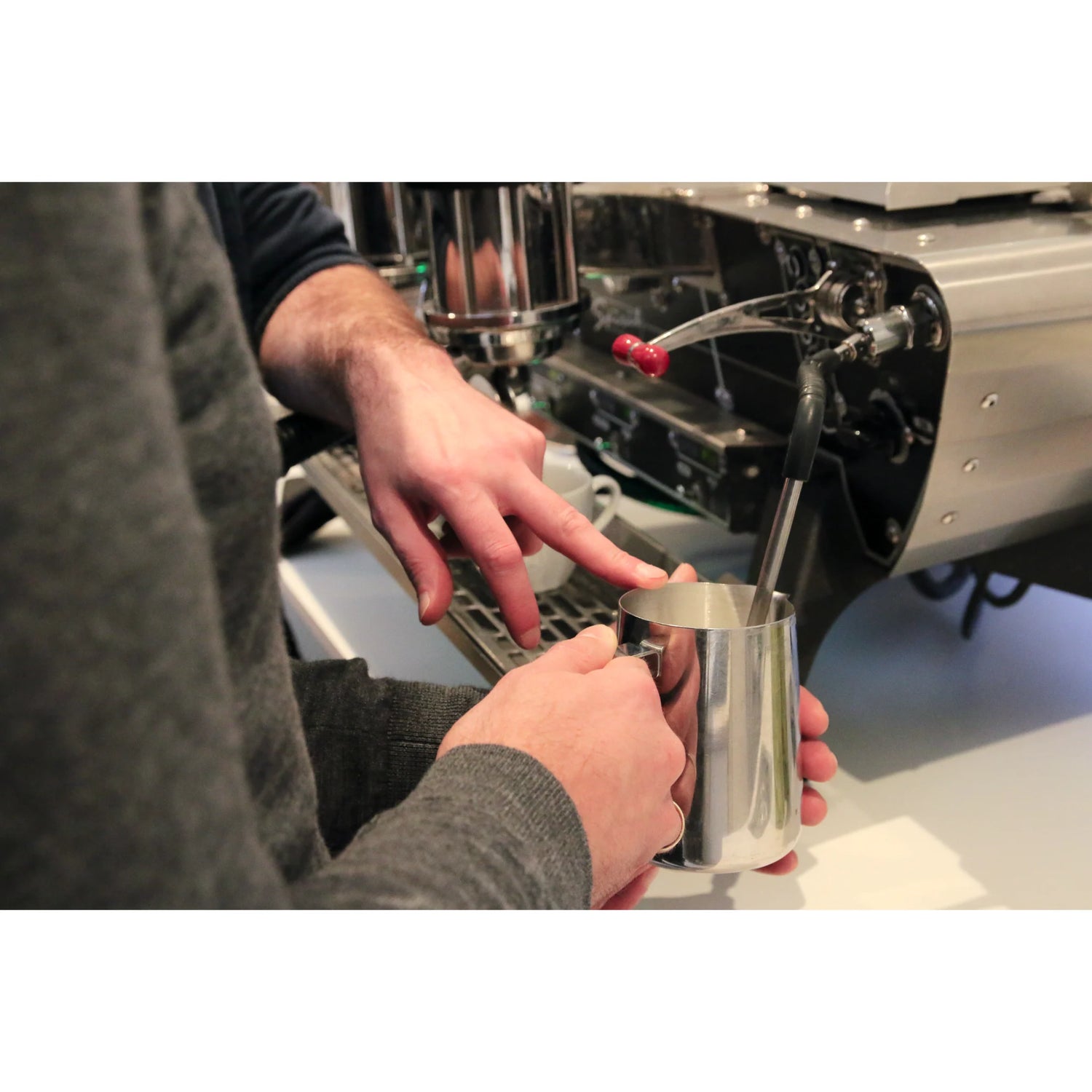 Een barista-instructeur laat zien hoe je met de juiste techniek melk schuimt voor cafe latte in de Barista Workshop in Amsterdam.