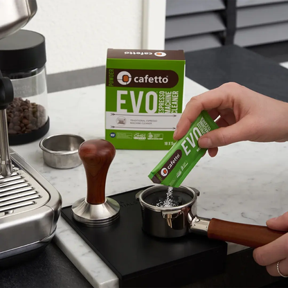 Hand giet Cafetto EVO blindfilterpoeder in portafilter om espressomachine zetgroep te reinigen.