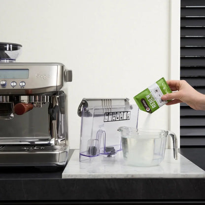 Een zakje Cafetto Renew naast het losse waterreservoir van een espressomachine