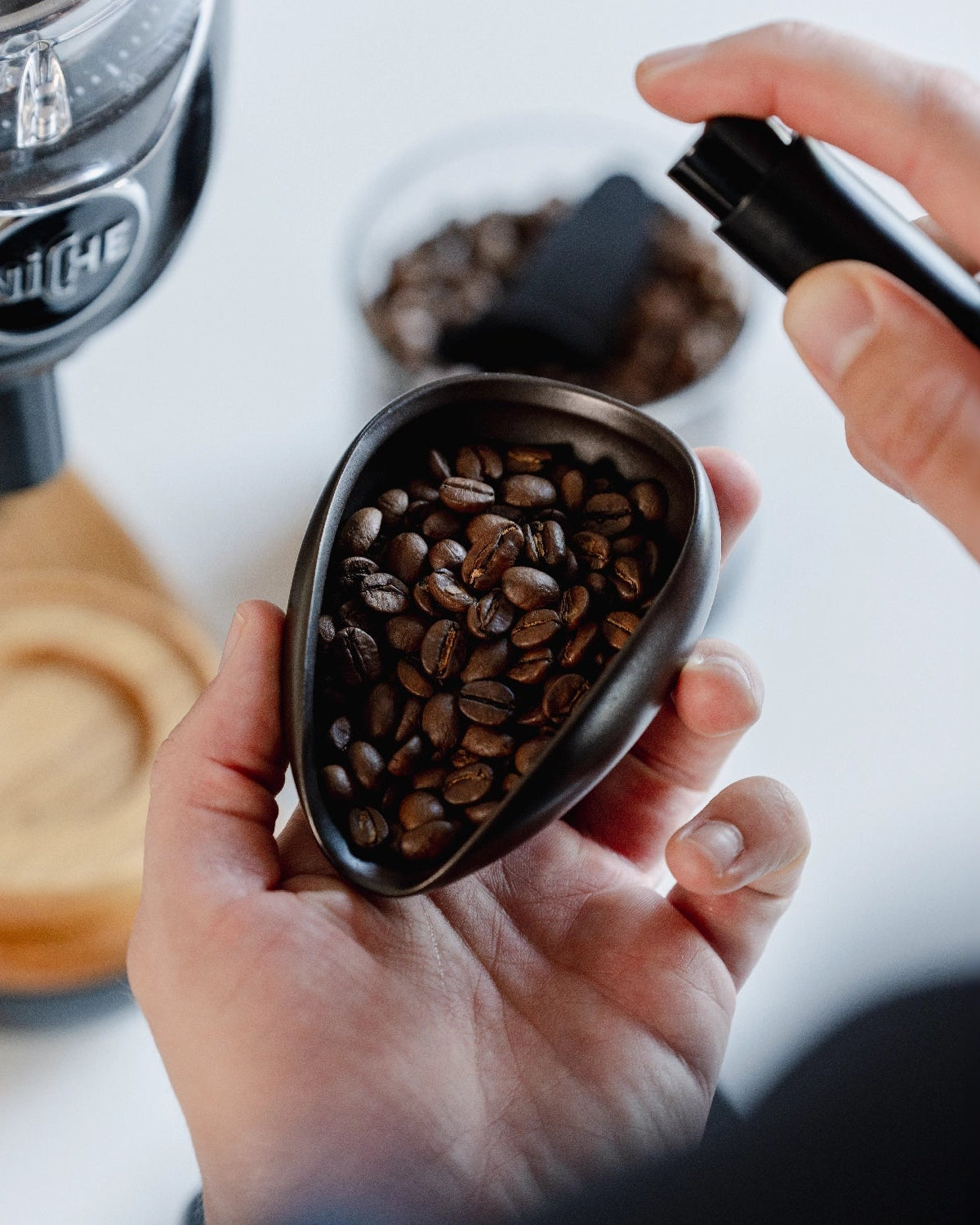 Koffiebonen in de zwarte Coffee Dosing Tray, met een spray erboven