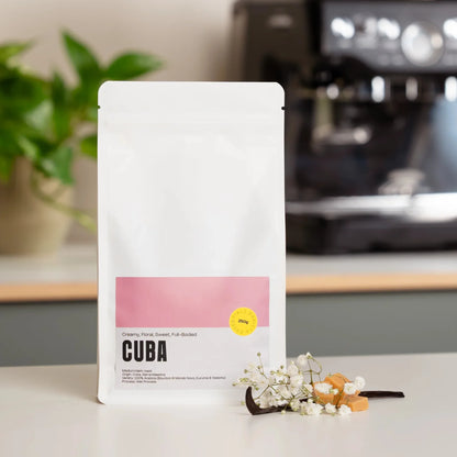 Zak Cuba specialty coffee met romige en bloemige smaaktonen naast een Sage espressomachine op het aanrecht.