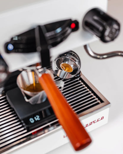 Naked portafilter met convex filterbakje van 58 mm boven een kopje op de weegschaal