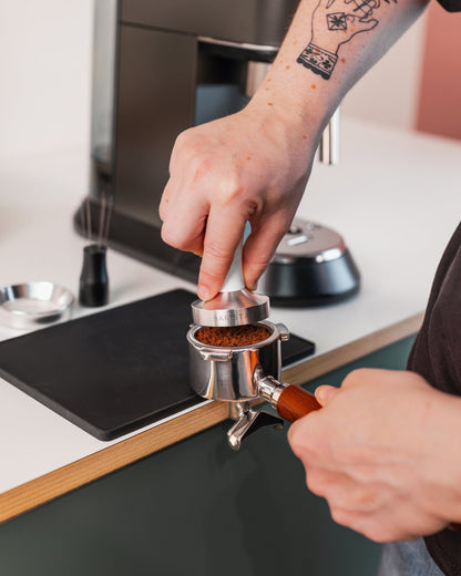 Hand op de wit tamper tijdens het tampen