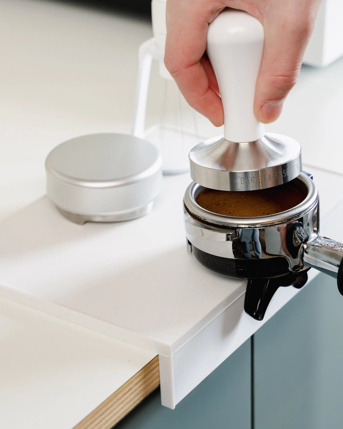 Koffie aandrukken op de grote witte tampermat met hoek