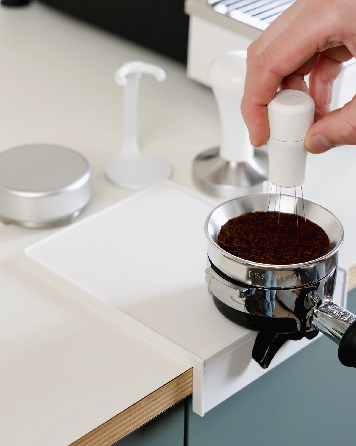 Koffie aandrukken op de kleine witte tampermat met hoek