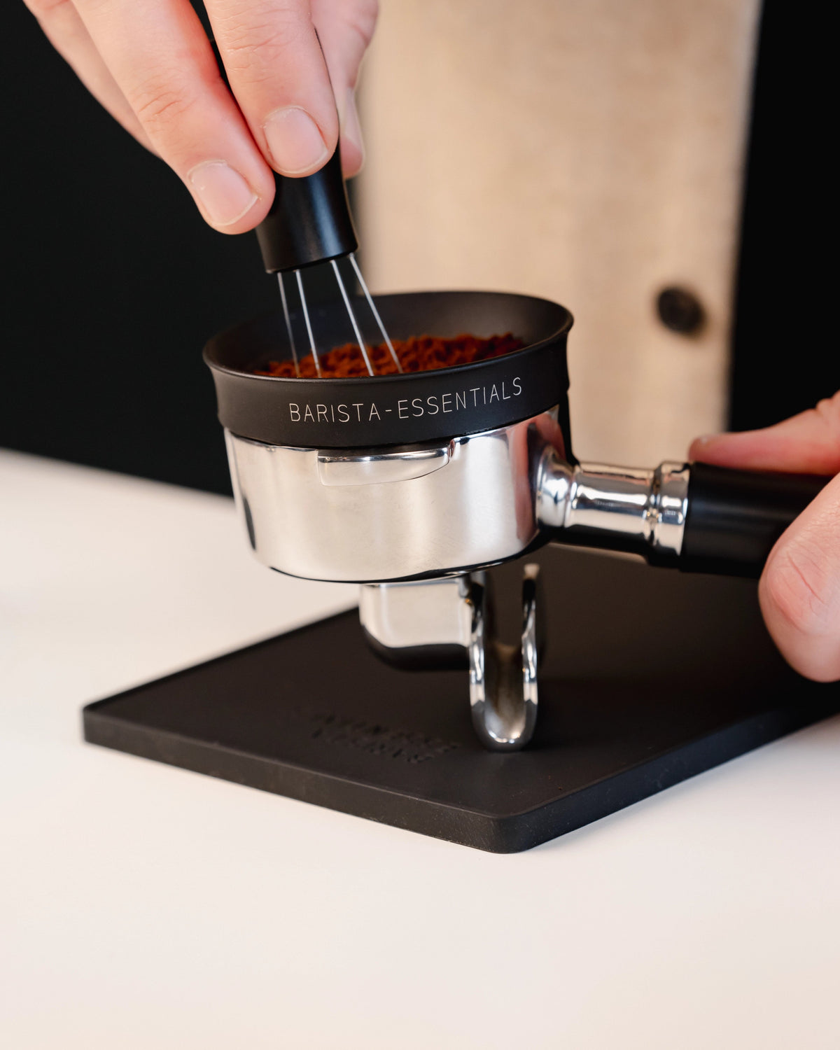 Portafilter op de kleine zwarte tampermat met hoek tijdens het verdelen van koffie