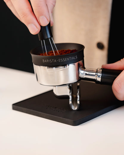 Portafilter op de kleine zwarte tampermat met hoek tijdens het verdelen van koffie