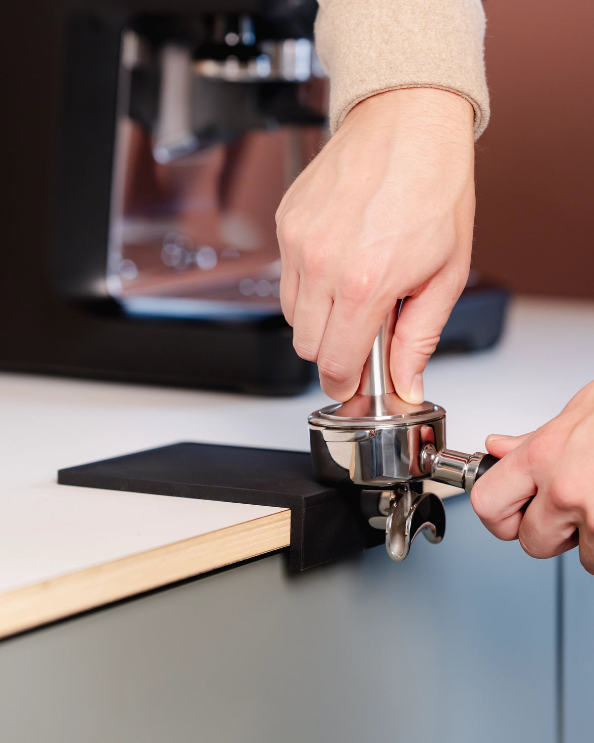 Koffie aandrukken met een portafilter op de kleine zwarte tampermat met hoek