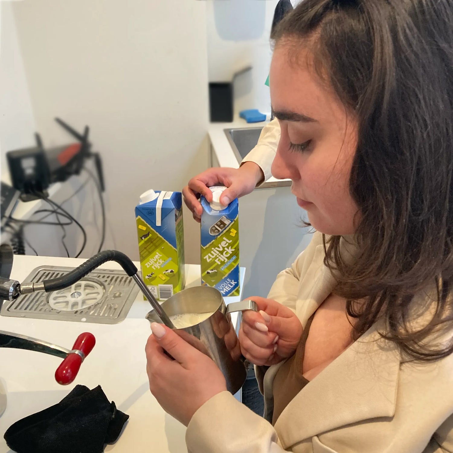 Deelneemster oefent met het schuimen van melk voor een cappuccino tijdens de workshop.