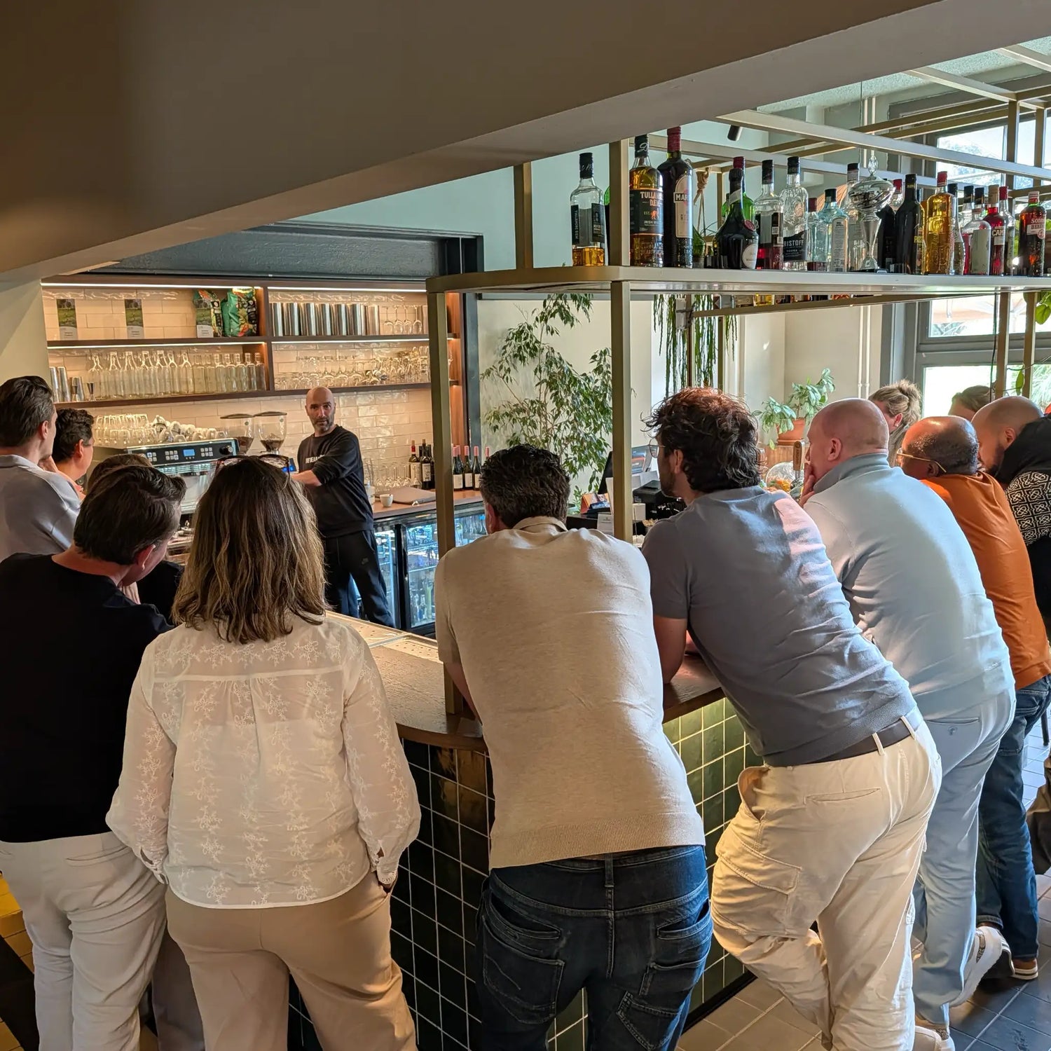 Deelnemers kijken toe terwijl Geert-Jan de Baristaman uitlegt hoe je cappuccino maakt op een professionele espressomachine tijdens een zakelijke barista workshop.