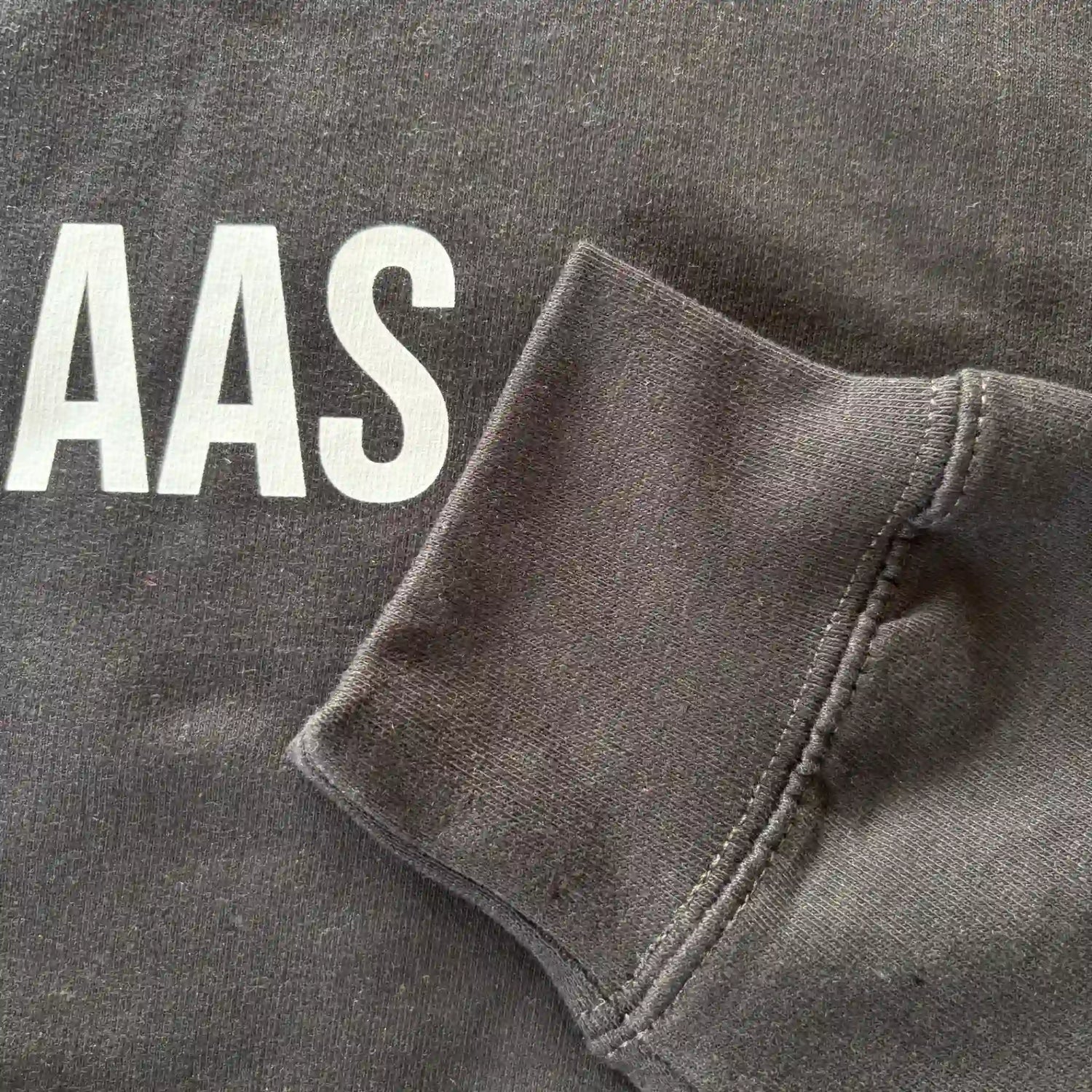 Detail van mouw en opdruk van het zwarte “KOFFIEBAAS” sweatshirt voor koffieliefhebbers