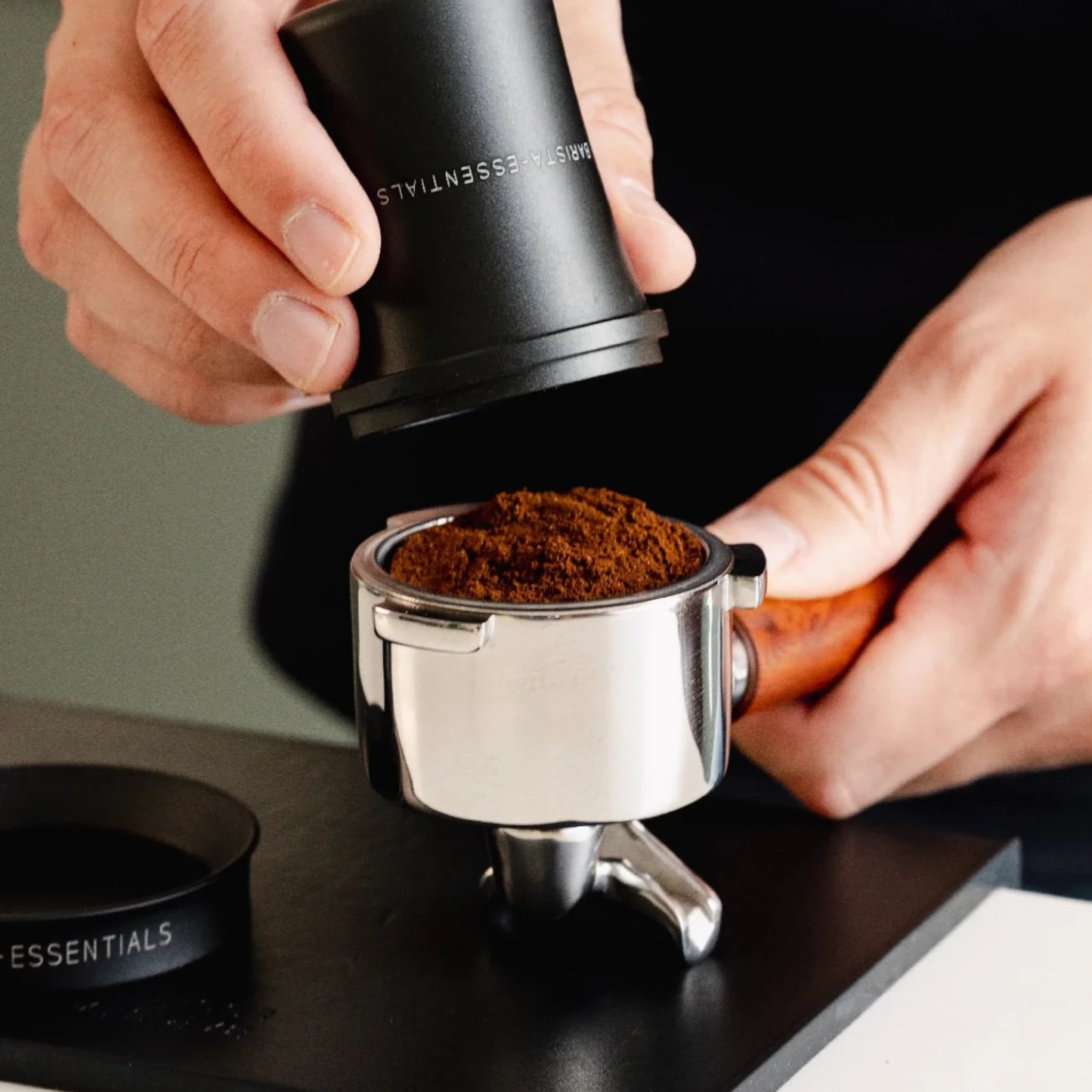 Gemalen koffie wordt vanuit de zwarte Doseerbeker V2 51mm in een portafilter overgezet zonder morsen