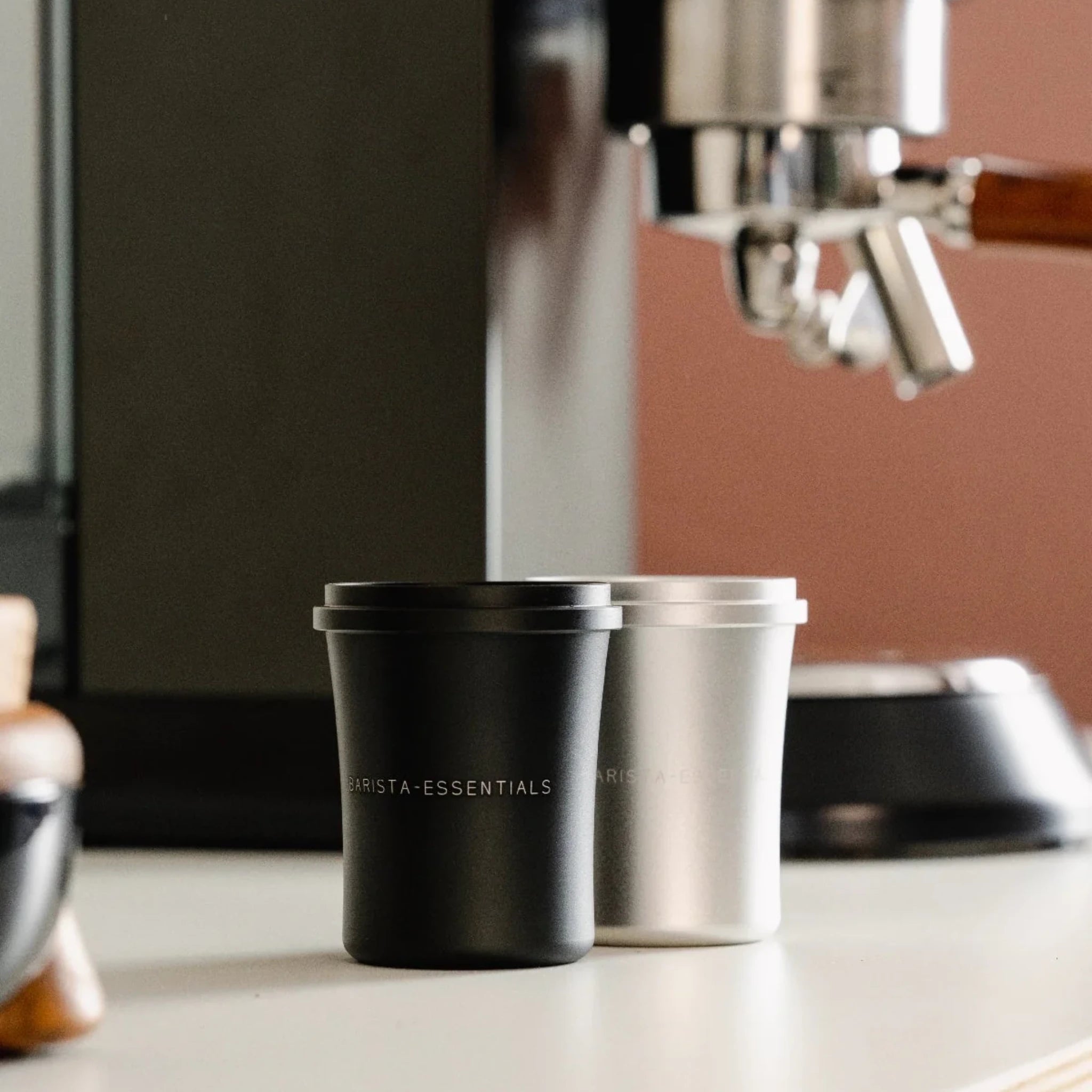 Doseerbeker V2 51mm in zwart en zilver naast een espressomachine voor single dosing thuis