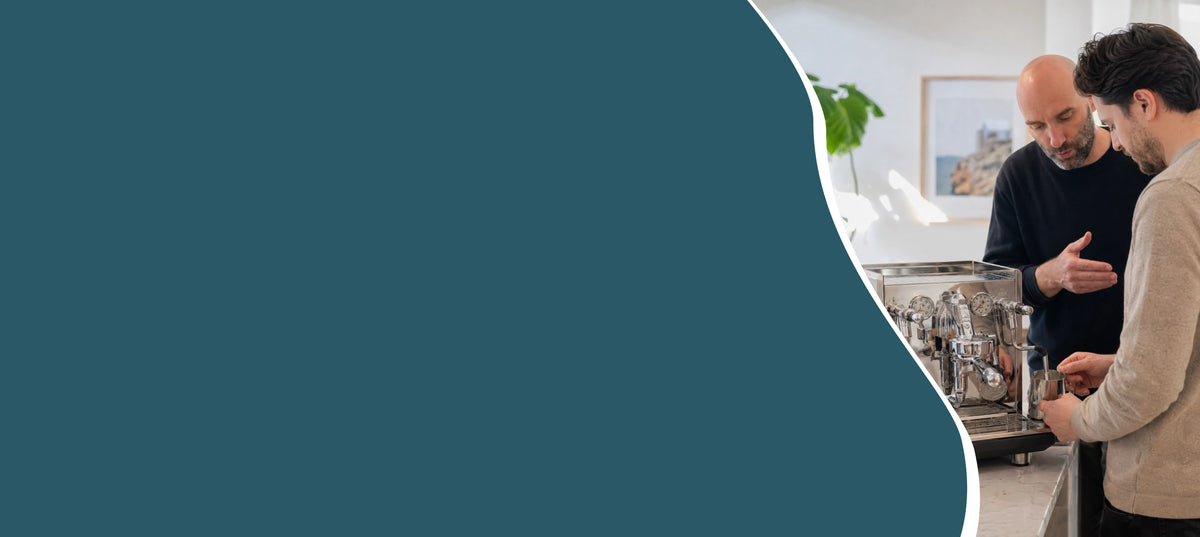 Hero banner met Geert-Jan de Baristaman die thuis persoonlijke barista-uitleg geeft op de ECM-espressomachine van een deelnemer.