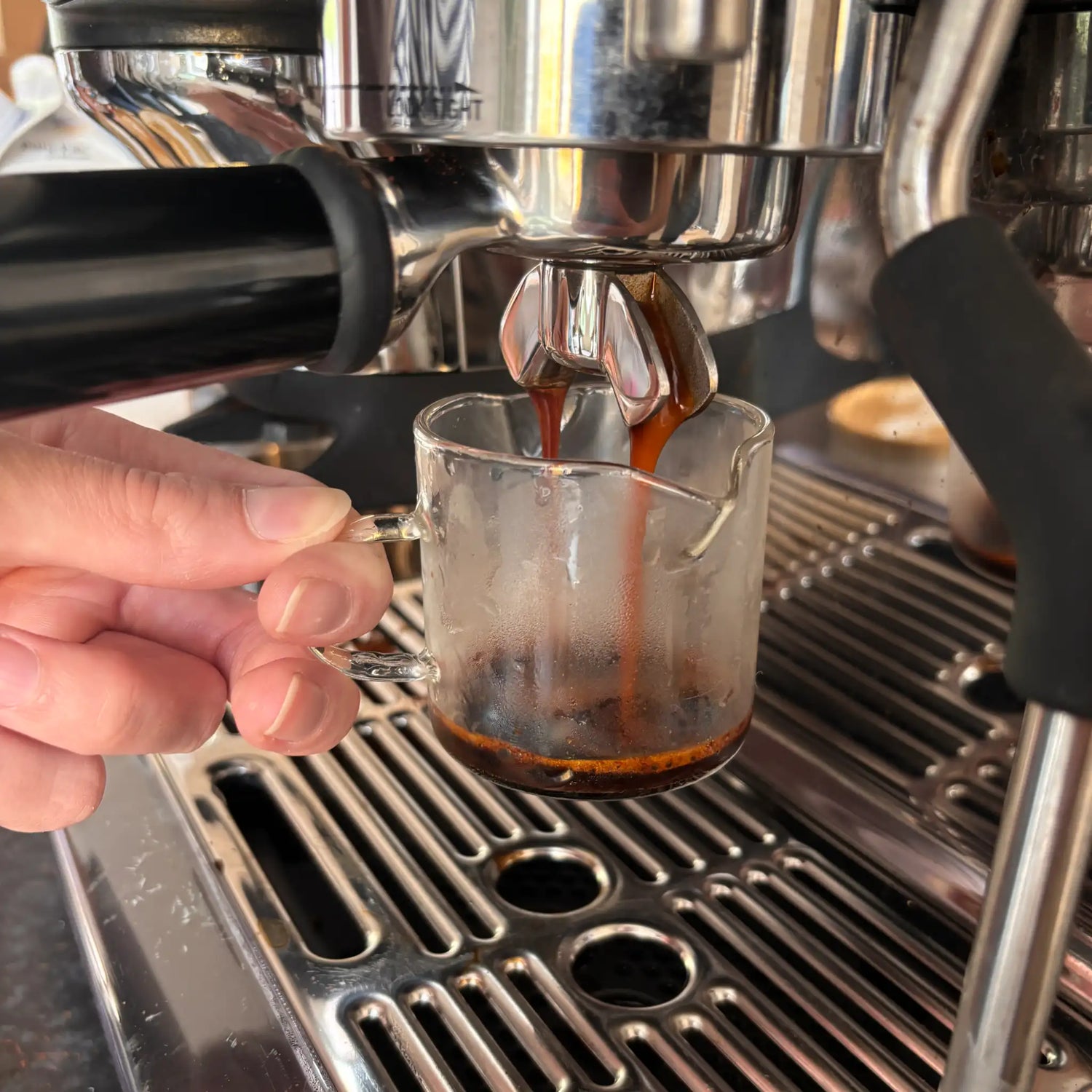 Espresso-extractie uit een Sage Barista Express Impress in een shotglas tijdens een workshop over crema body en koffiekeuze
