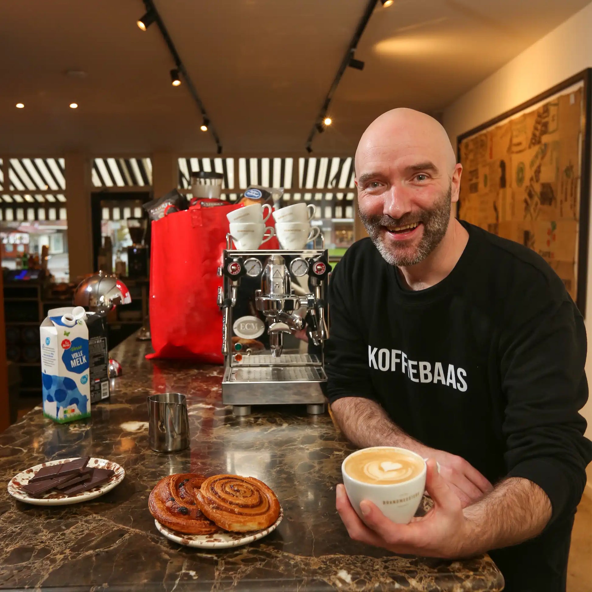 Geert-Jan van der Molen geeft privé barista coaching aan huis en serveert een latte tijdens een persoonlijke espresso workshop met professionele espressomachine.