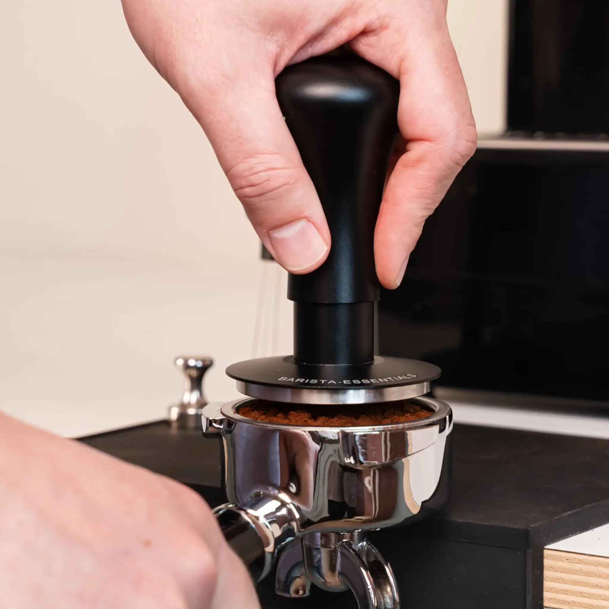 Zwarte gekalibreerde klik tamper wordt recht op een gevulde espresso portafilter gedrukt voor constante tampdruk.