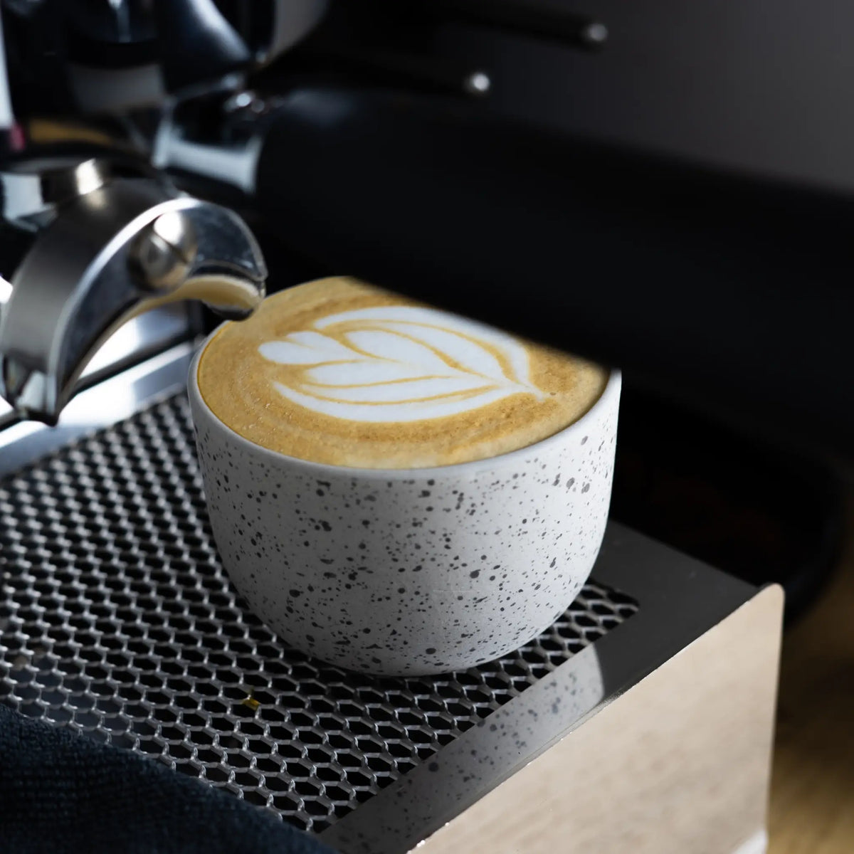 Gestippeld kopje met latte art op een espressomachine
