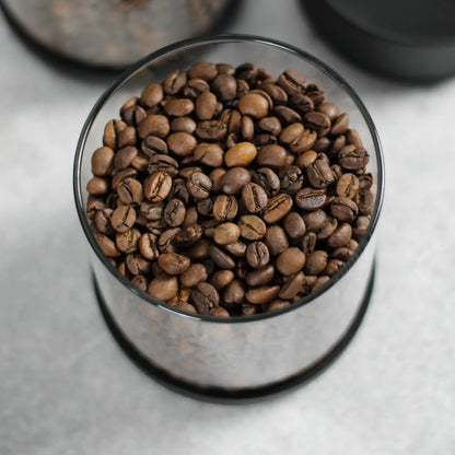 Bovenaanzicht van koffiebonen in een geopende glazen koffiebus