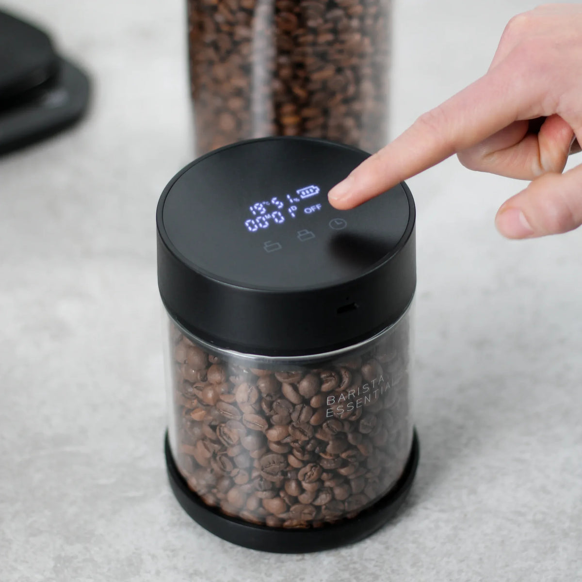 Hand bedient de Pro-deksel op een glazen bus met koffiebonen