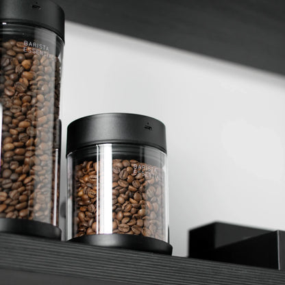Glazen koffiebussen in verschillende hoogtes met zwarte deksels