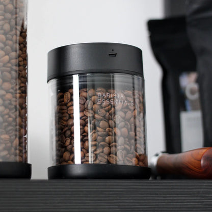 Glazen koffiebus met zwarte deksel en hele koffiebonen