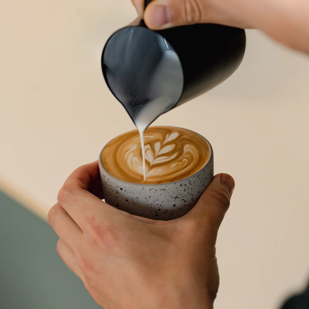 Hand schenkt melk in een gestippeld kopje
