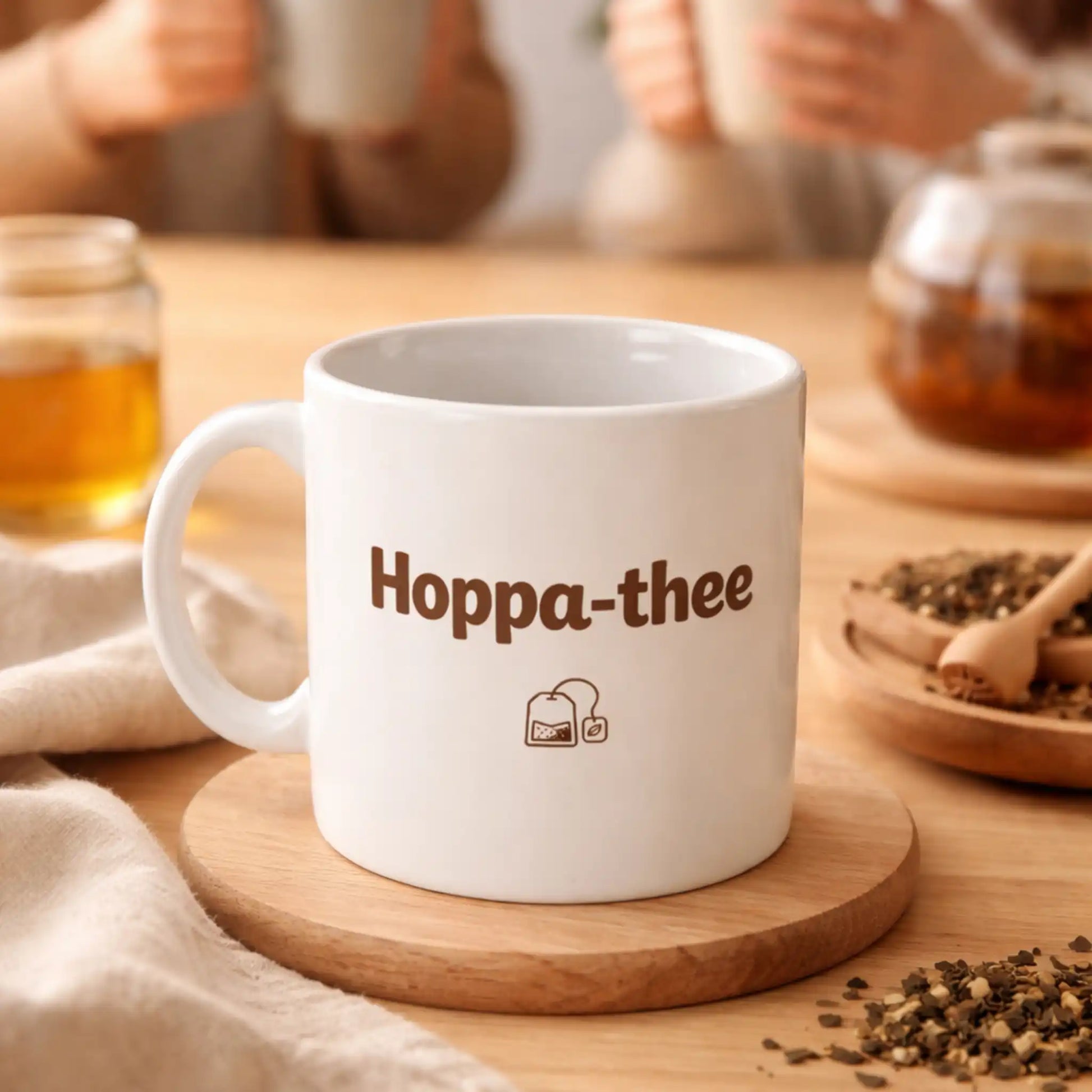 Sfeerbeeld van de Hoppa-thee mok op tafel, met mensen op de achtergrond die samen thee drinken in een warme en ontspannen setting.