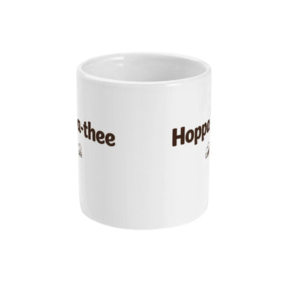 Zijaanzicht van witte keramische thee mok met de tekst Hoppa-thee in een rustig en minimalistisch ontwerp.