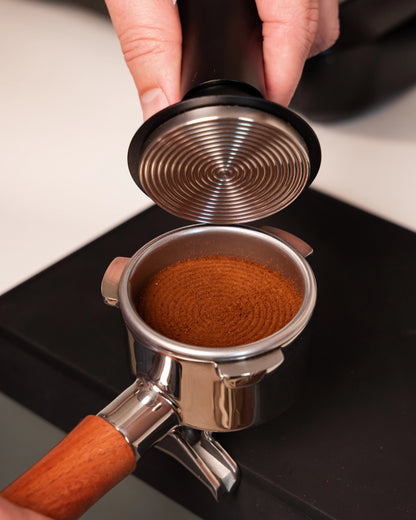 Geribbeld tampvlak van de 53,3 mm klik-tamper boven aangedrukte koffie
